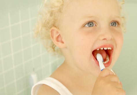 [Translate to Spanish:] kid cleaning teeth